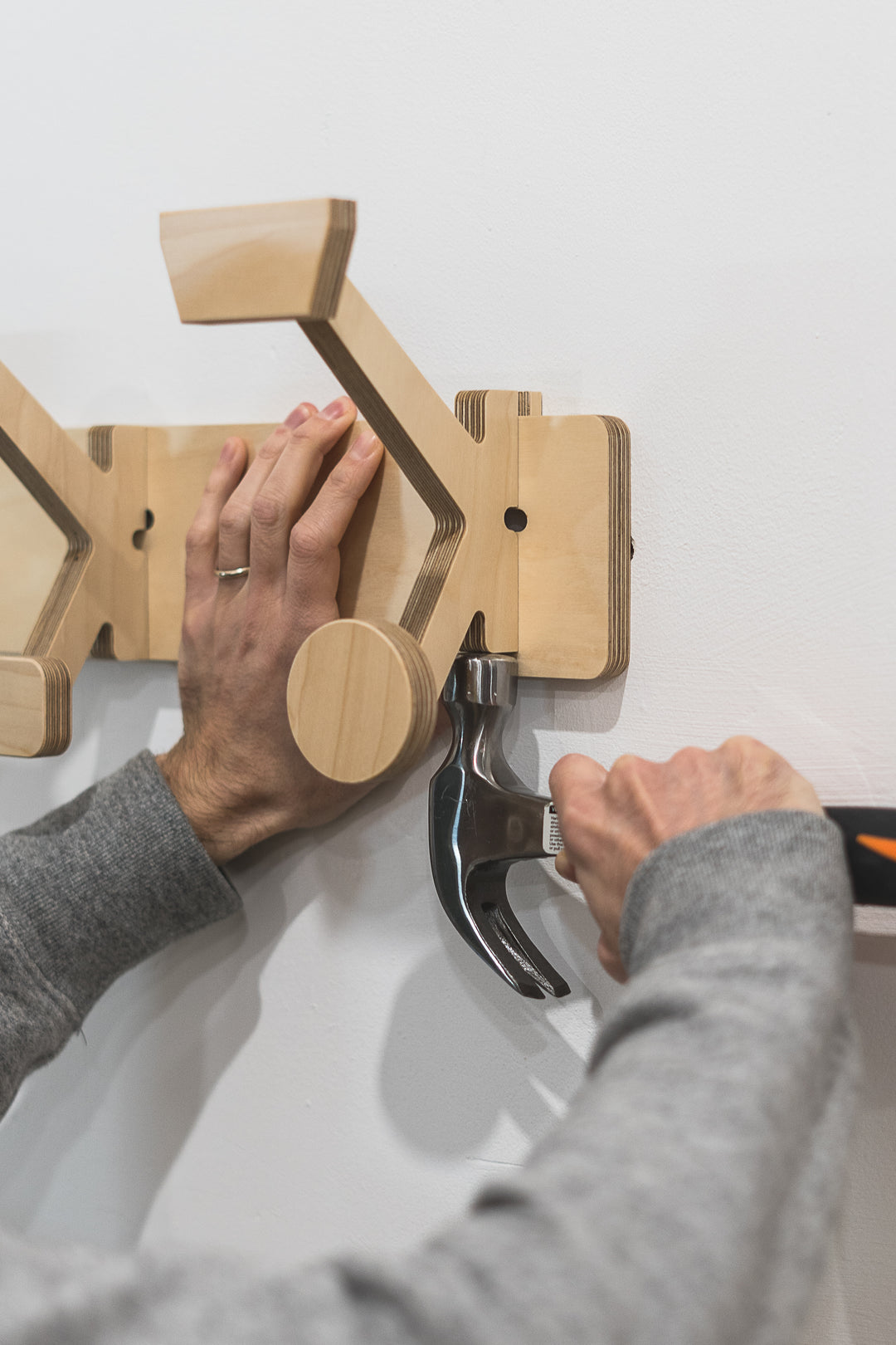 Artesano instalando un colgador de pared de madera con un martillo